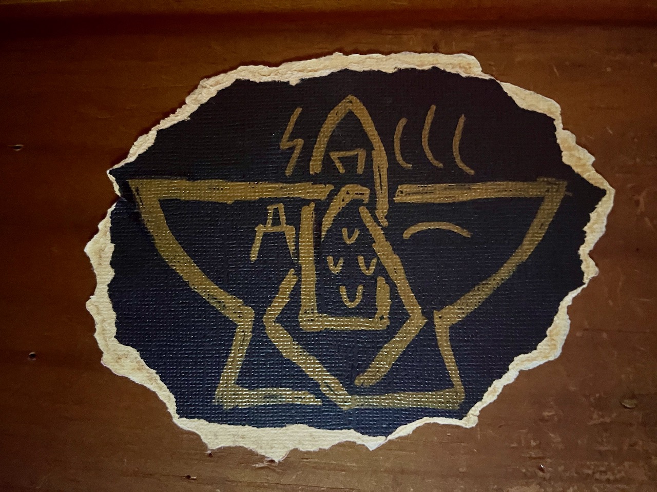 An image in gold ink on a black background. The symbol of the Sculptor-of-Pieces (a stylized hammer and anvil made of interlocking shapes) is decorated with four smaller Antler-Tine symbols, representing Fracture, Anvil, Clouds, Land, Family, and City.